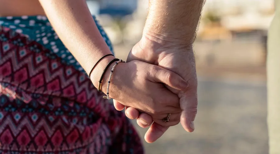 Immagine ravvicinata di una coppia che si tiene per mano. Altri sintomi della sclerosi multipla come affaticamento, tremori o problemi alla vescica e all'intestino possono interferire con la vita sessuale di una persona. 